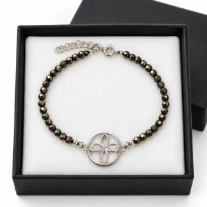 Pulsera de pirita facetada con sigilo circular y cierre de plata de ley sobre almohadilla blanca en caja negra.